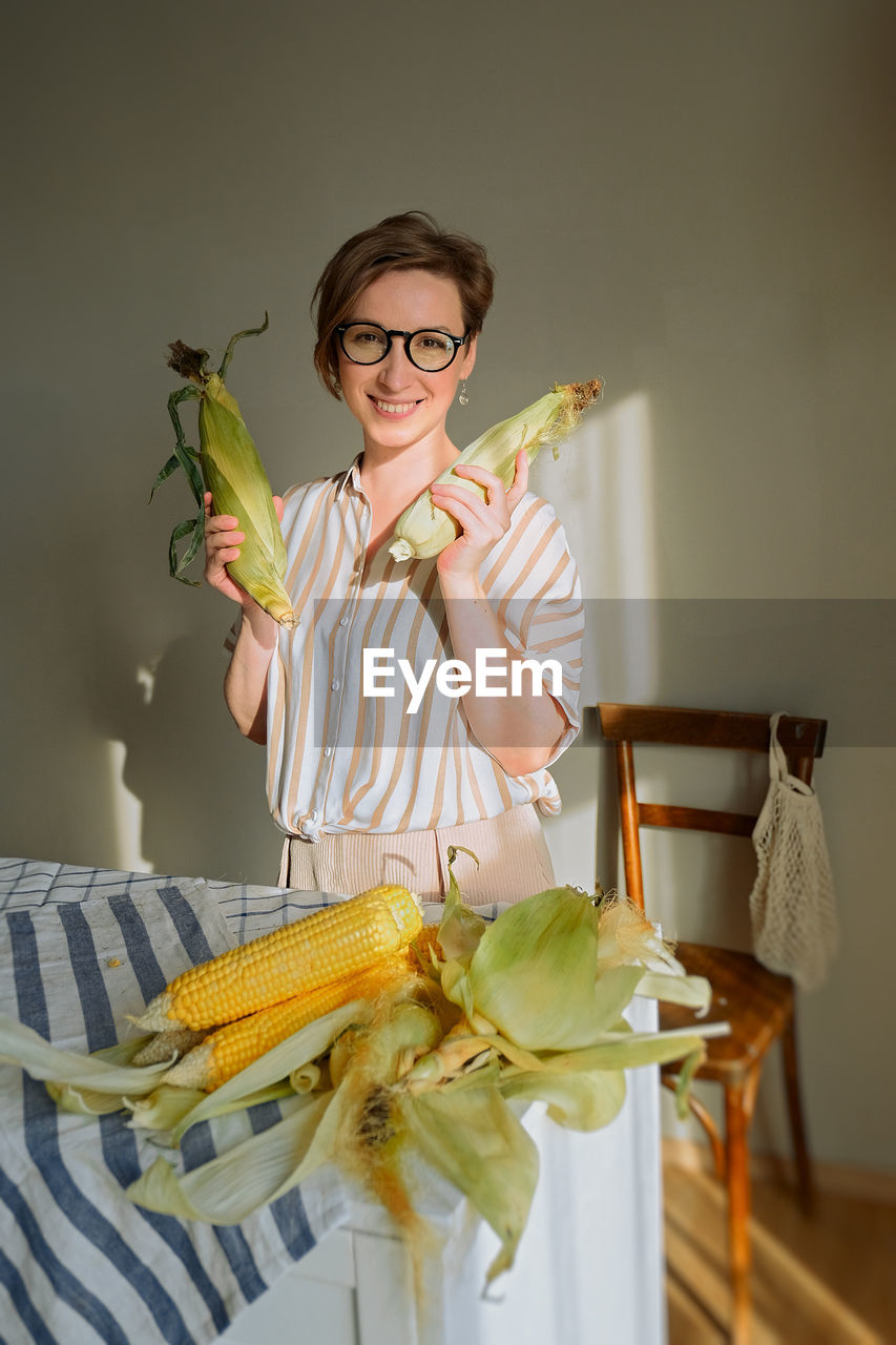 Portrait of woman holding corn at home