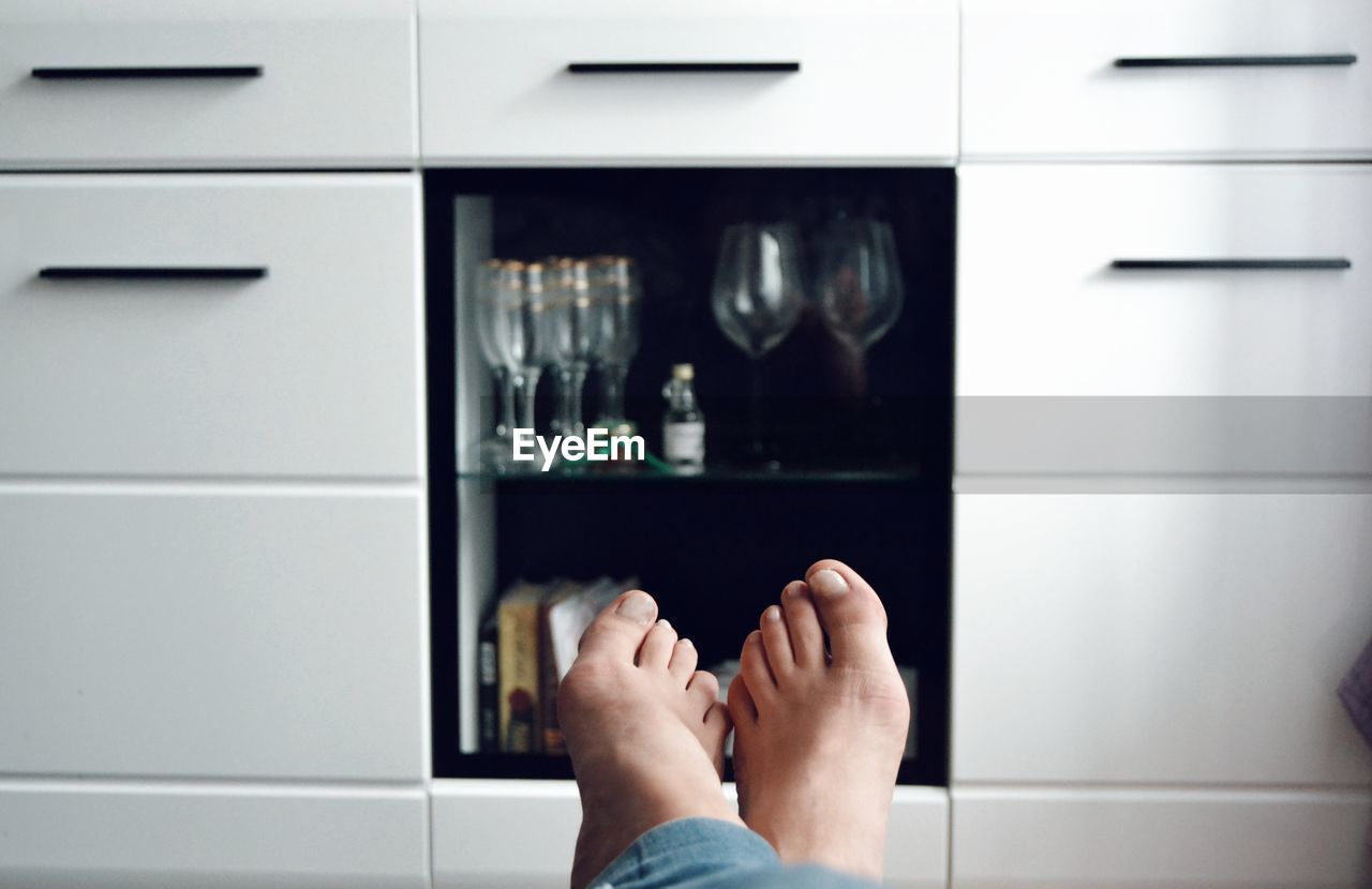 Low section of woman against shelves at home