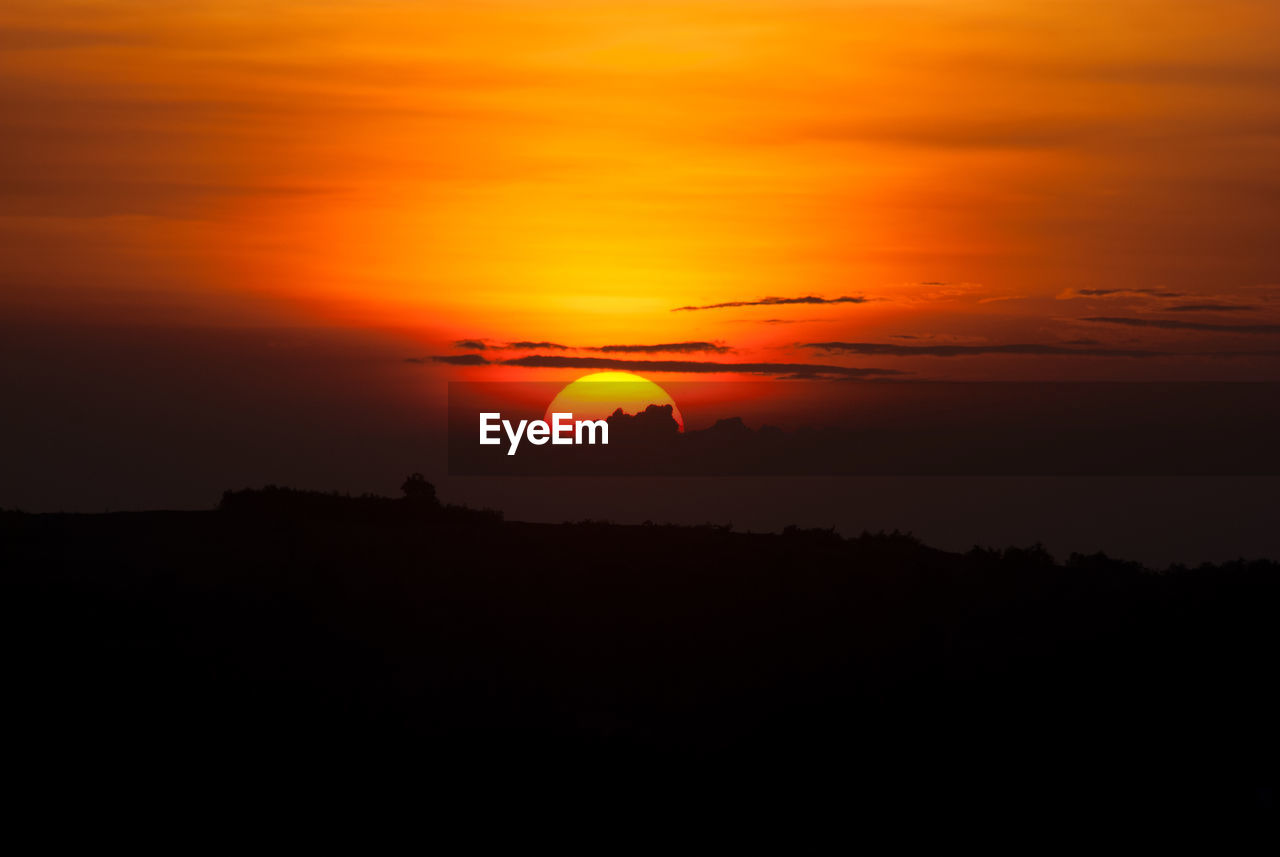 Scenic view of silhouette landscape against orange sky