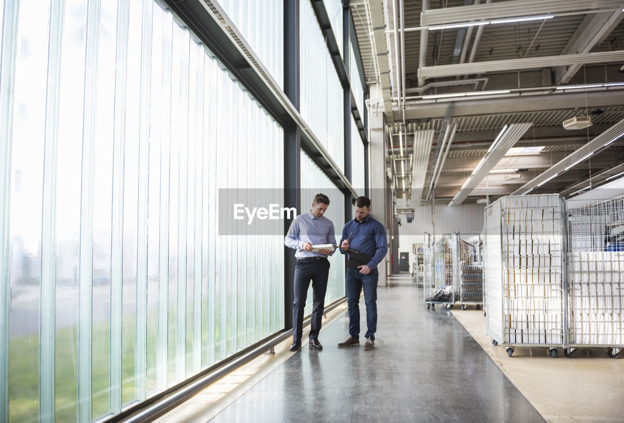 Two men in factory shop floor examining product