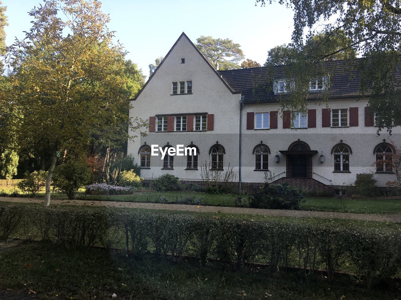 HOUSES AND TREES BY LAWN AGAINST SKY
