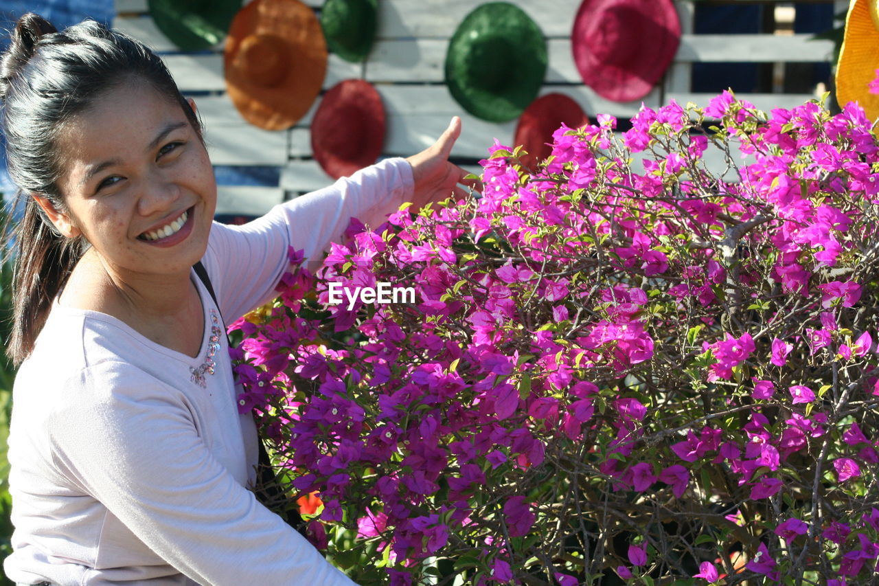 Portrait of smiling woman with purple flowering plants