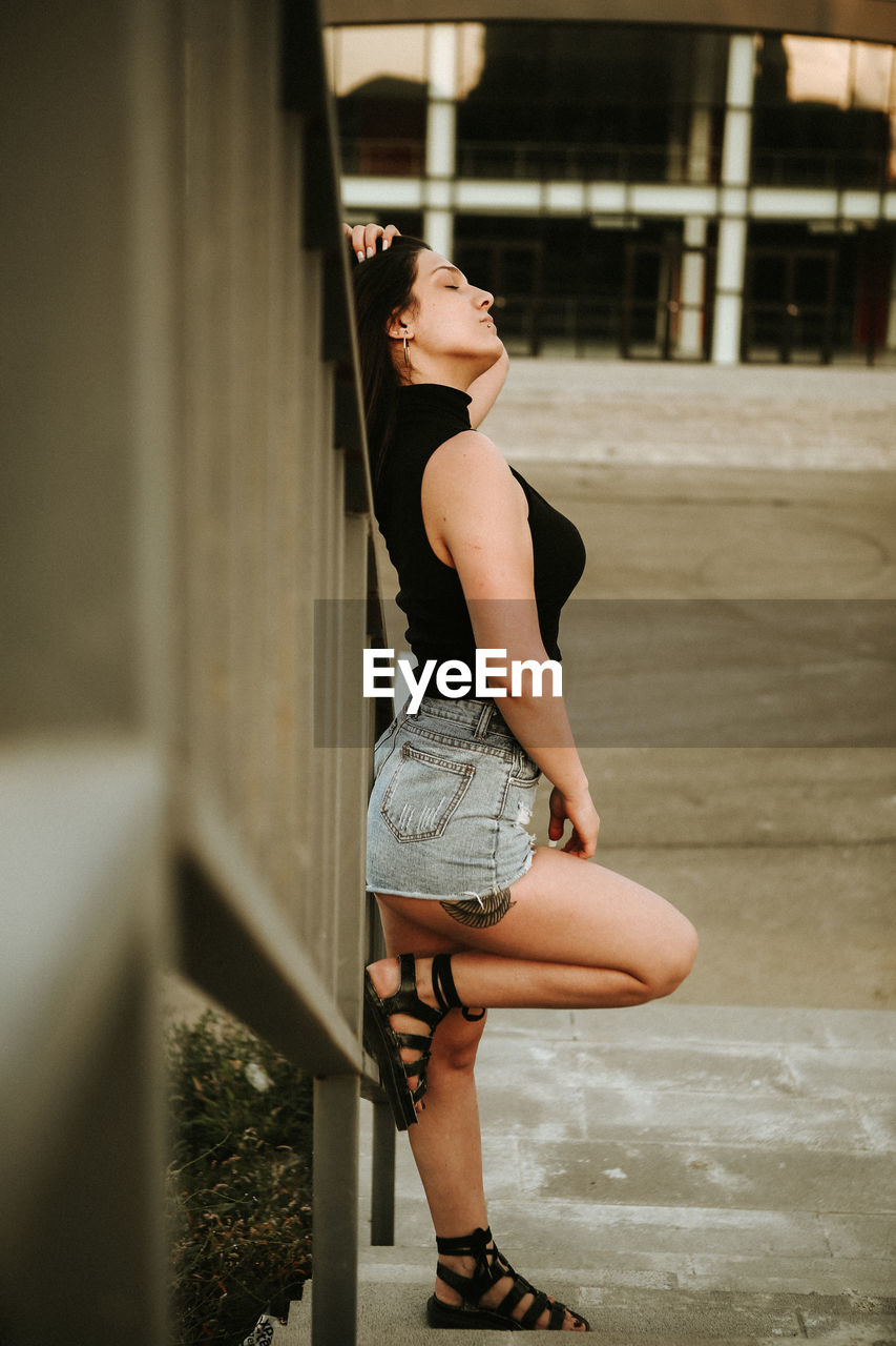 Fashionable young woman standing on steps in city