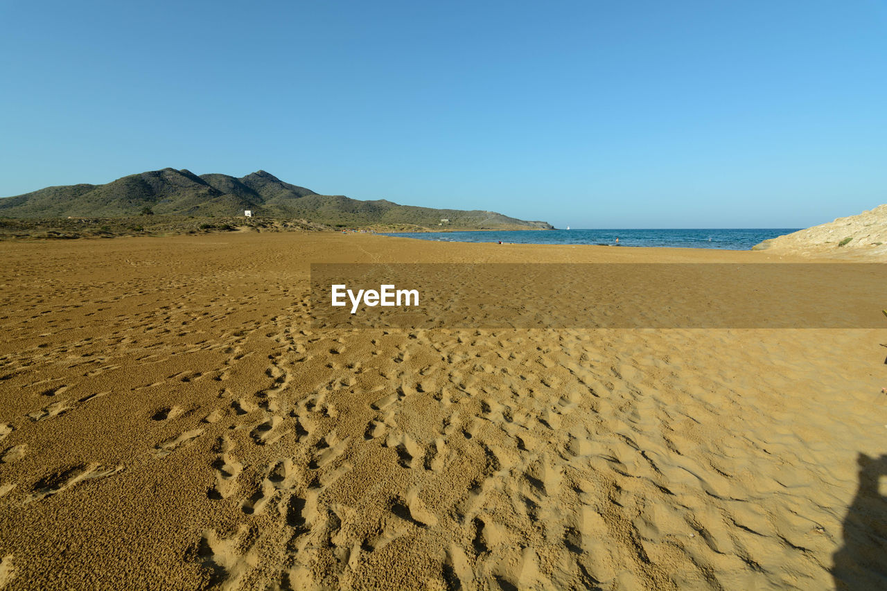 Scenic view of desert against clear blue sky