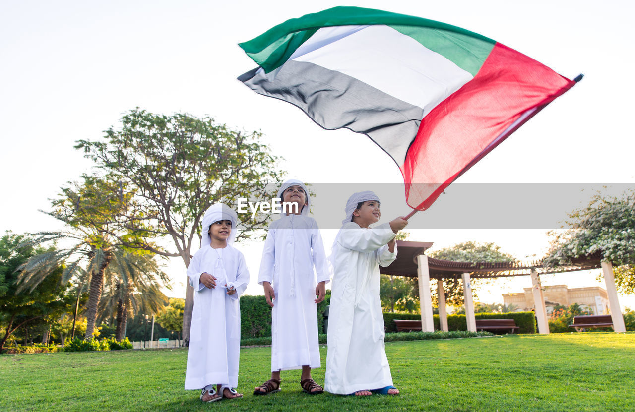 Children with united arab emirates flag standing on grassy field