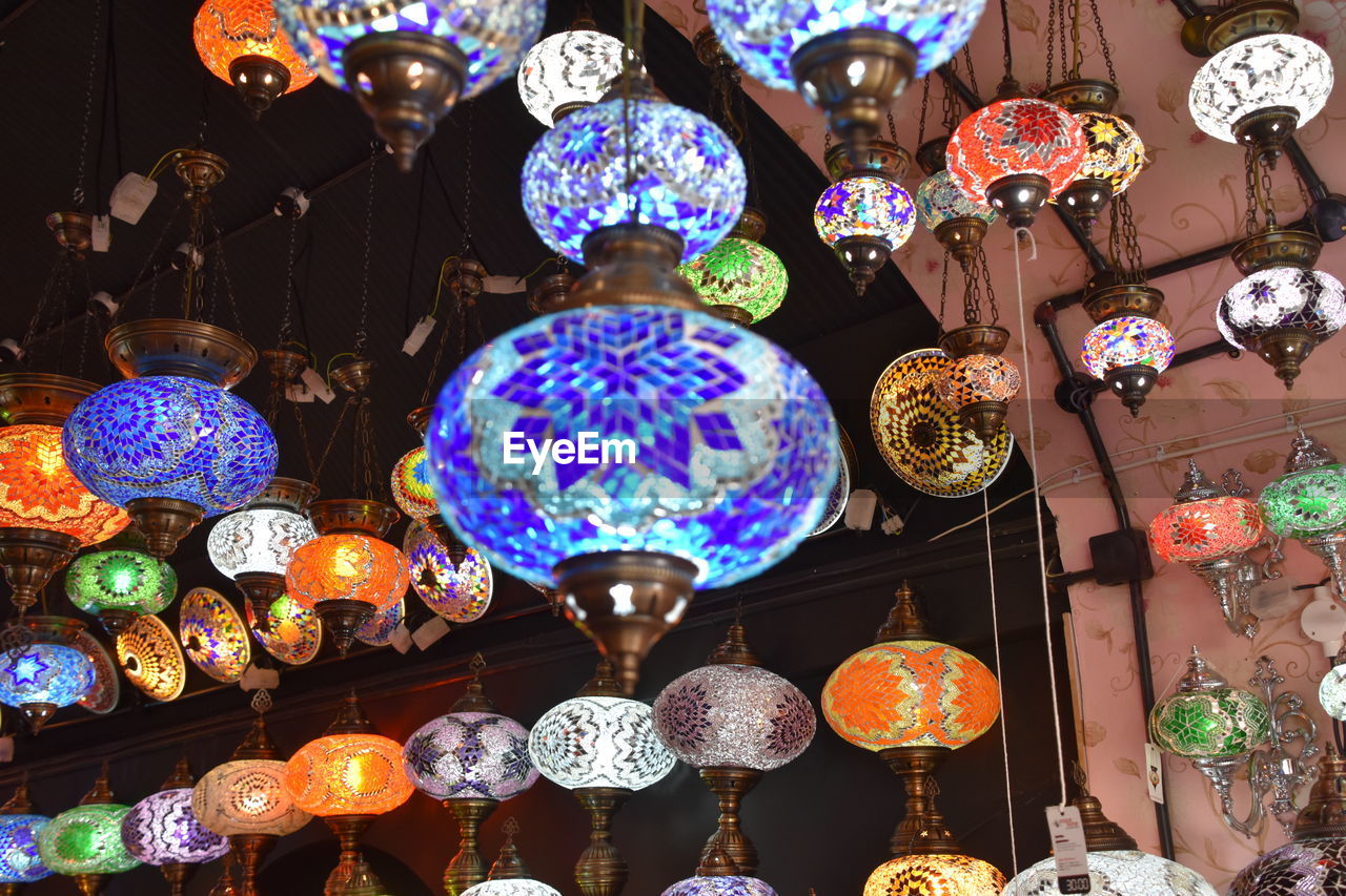 LOW ANGLE VIEW OF ILLUMINATED LANTERNS HANGING ON WALL