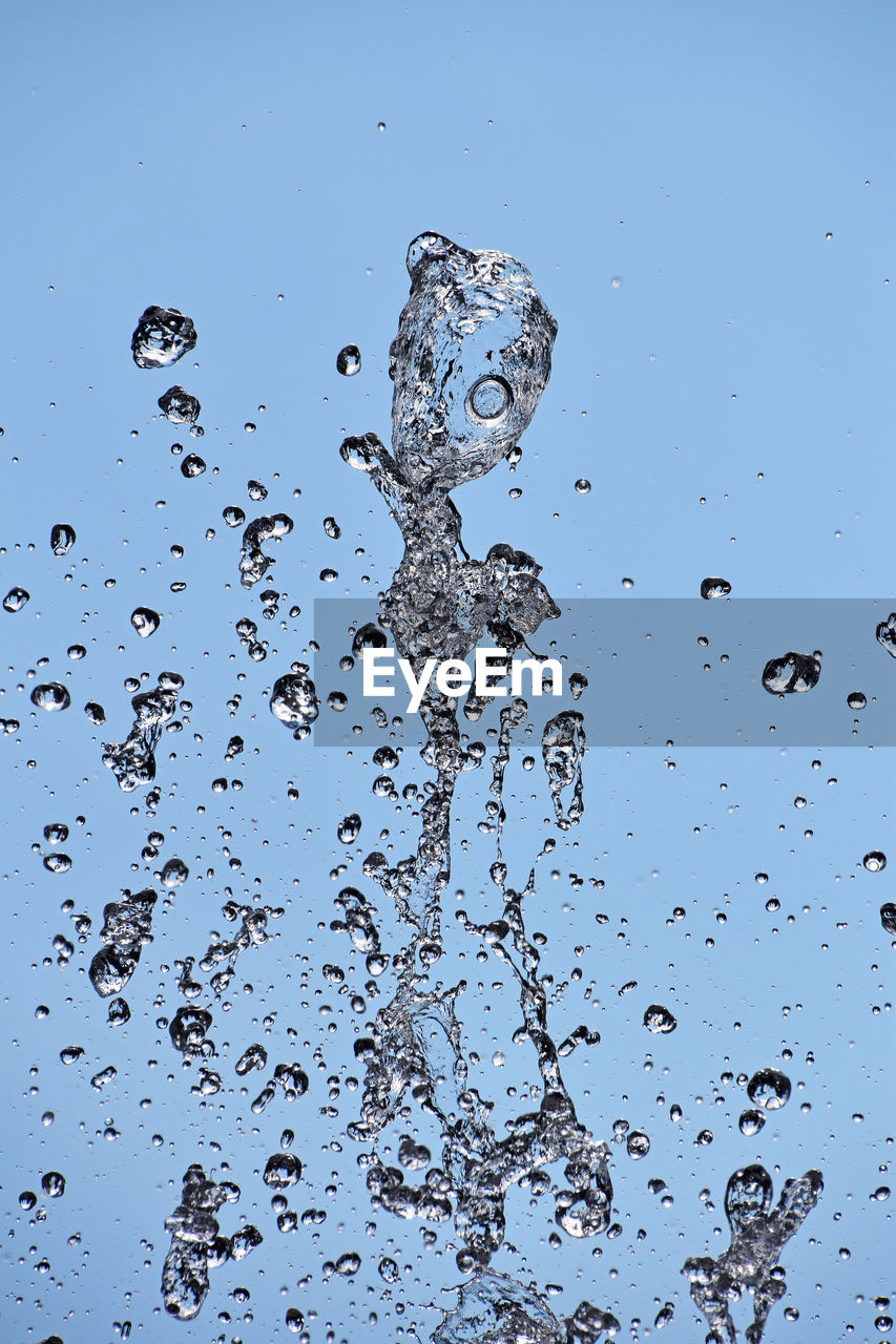 CLOSE-UP OF WATER SPLASHING AGAINST BLUE SKY