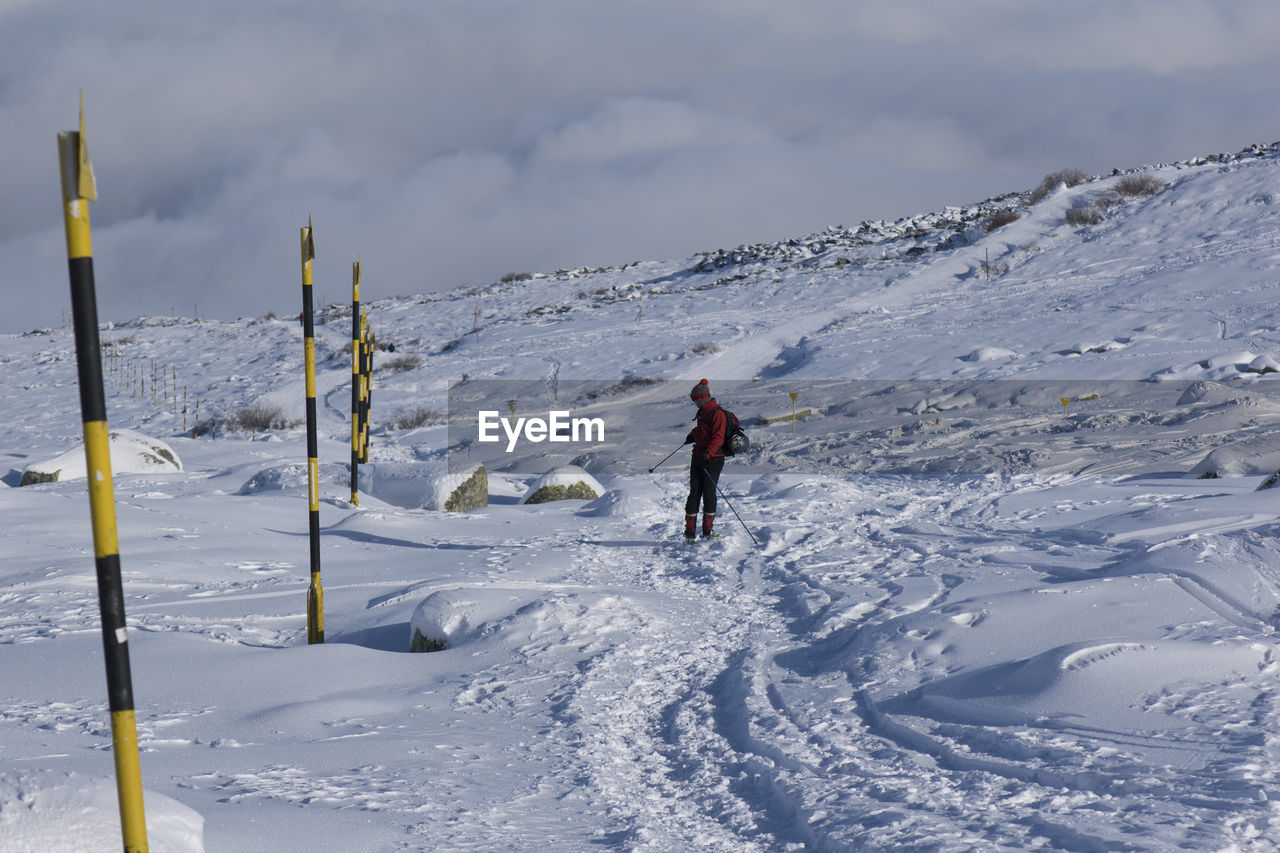 PEOPLE SKIING ON SNOWCAPPED MOUNTAIN AGAINST SKY