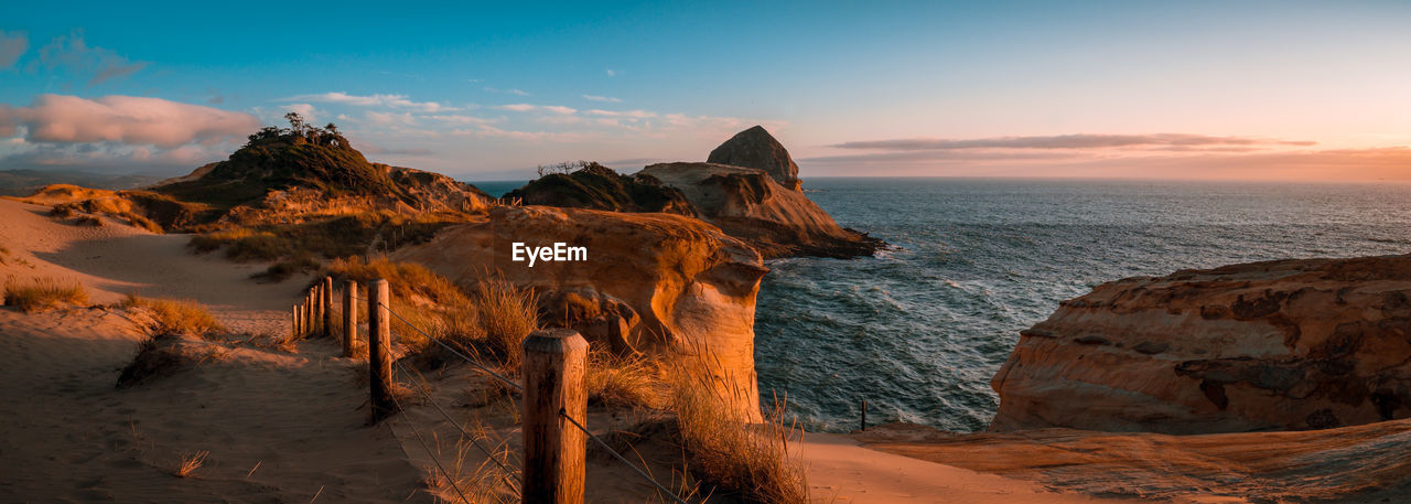 Rock formations on shore against sky during sunset