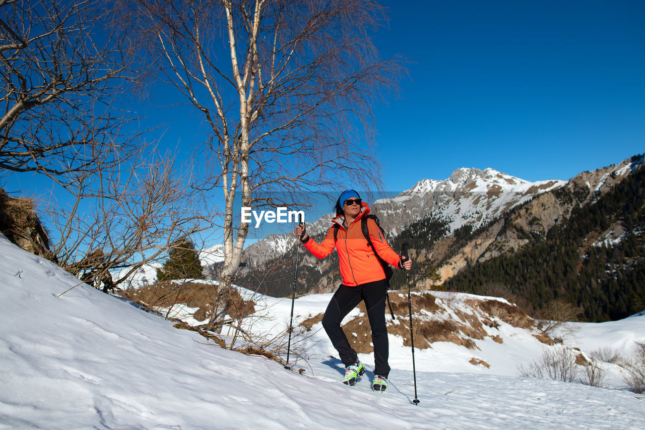 WOMAN ON SNOWCAPPED MOUNTAIN AGAINST CLEAR BLUE SKY