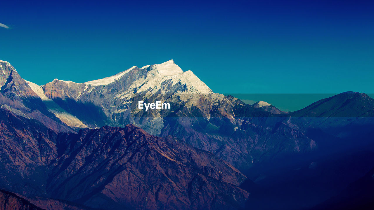 Scenic view of snowcapped mountains against clear blue sky