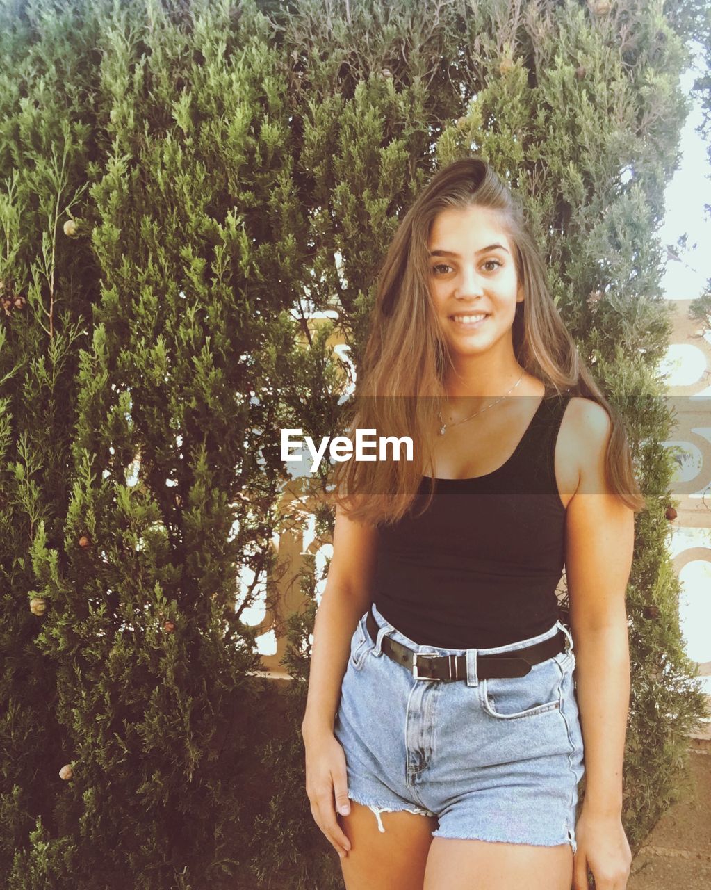 PORTRAIT OF SMILING WOMAN AGAINST PLANTS