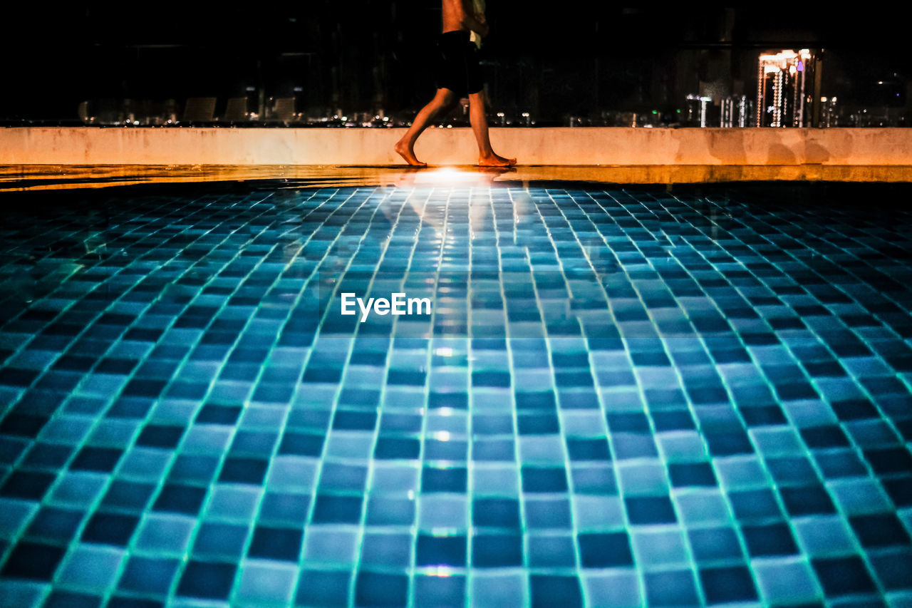 Low section of man walking on swimming pool