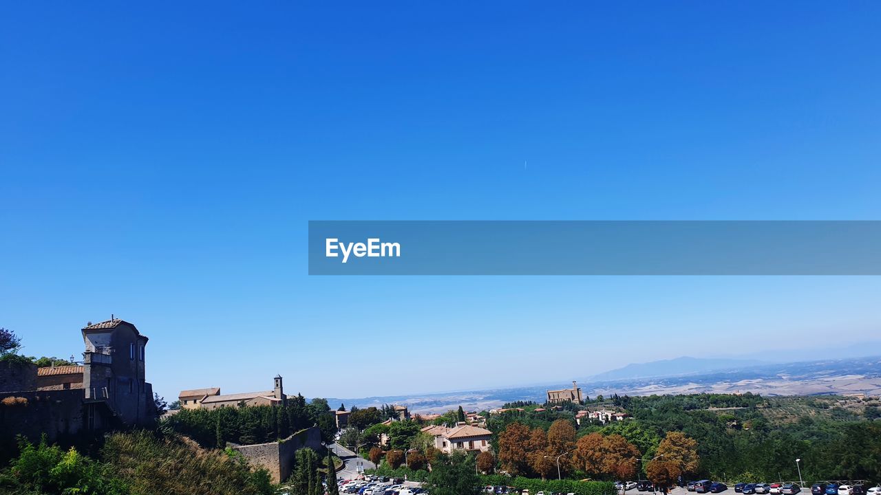 Buildings in city against clear blue sky