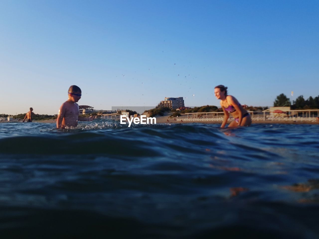 PEOPLE ENJOYING IN SWIMMING POOL AGAINST SEA