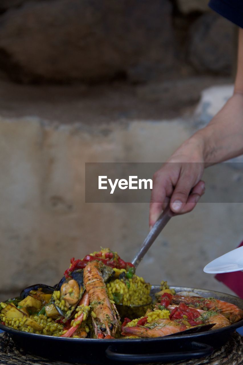 Midsection of person serving paella