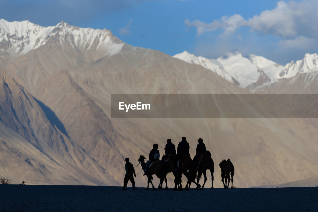 Group of people riding camels on mountain