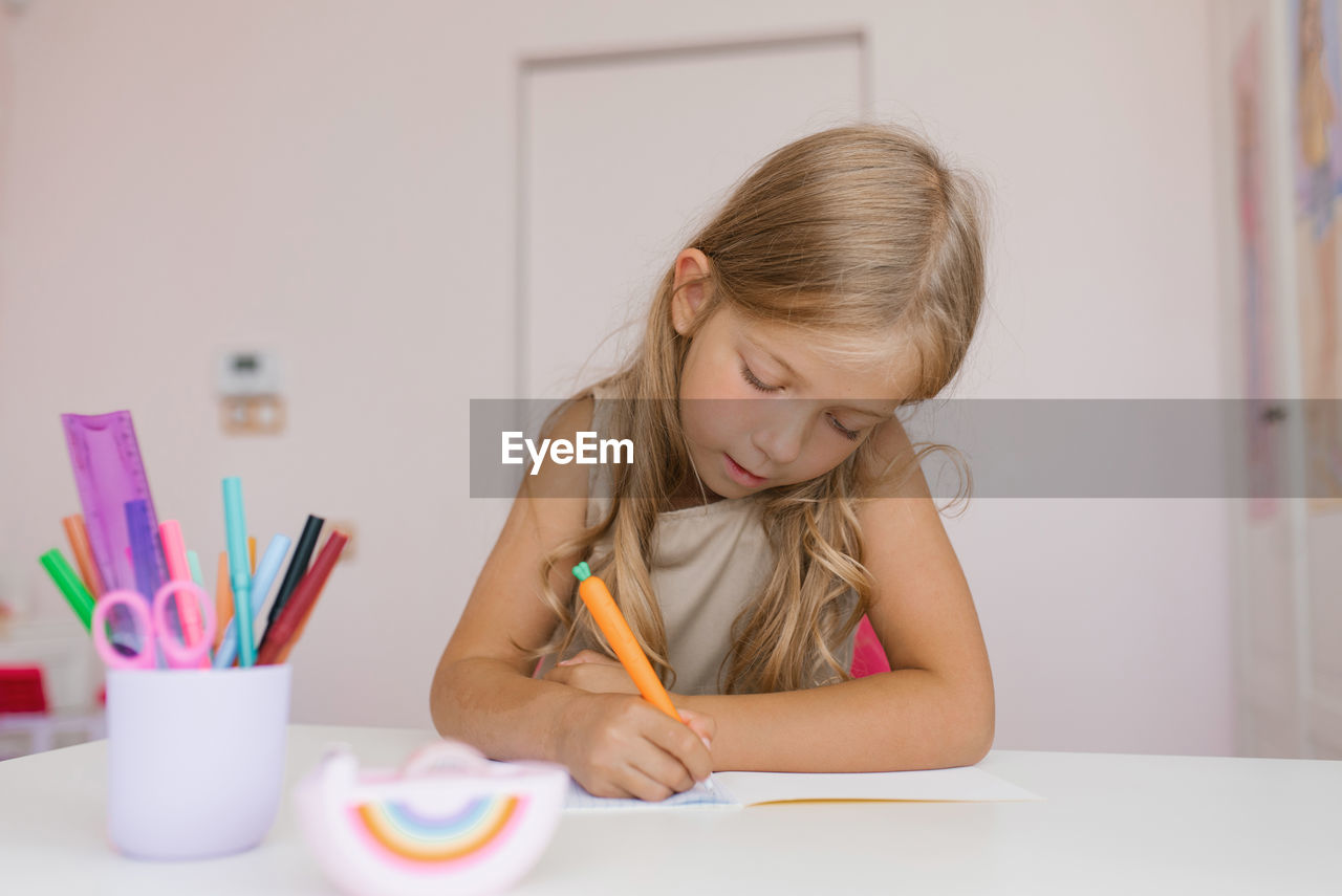 Seven year old girl does her homework while sitting at a table