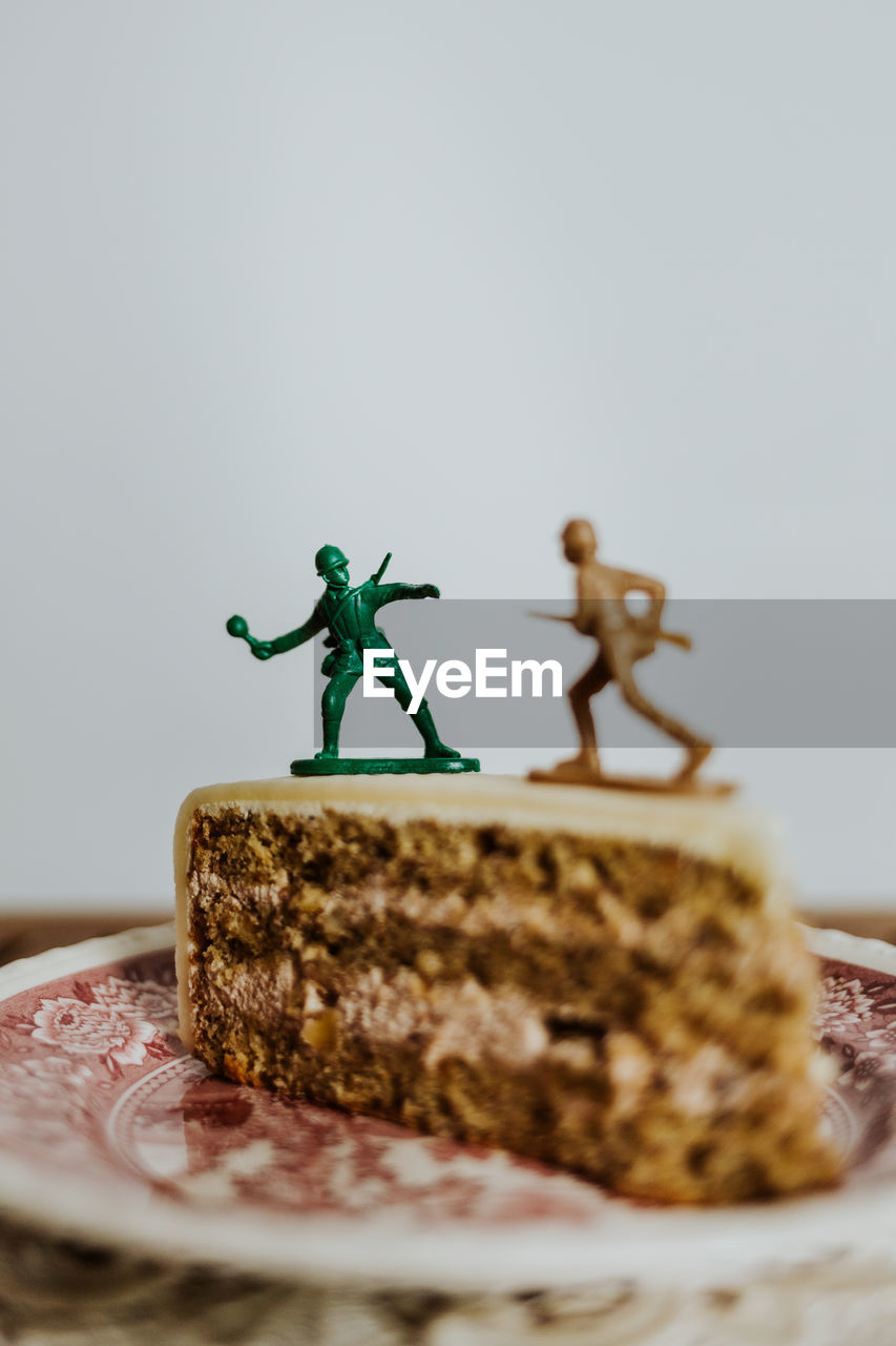 Two toy soldiers fighting on the top of a piece of cake about calories - close up - white background