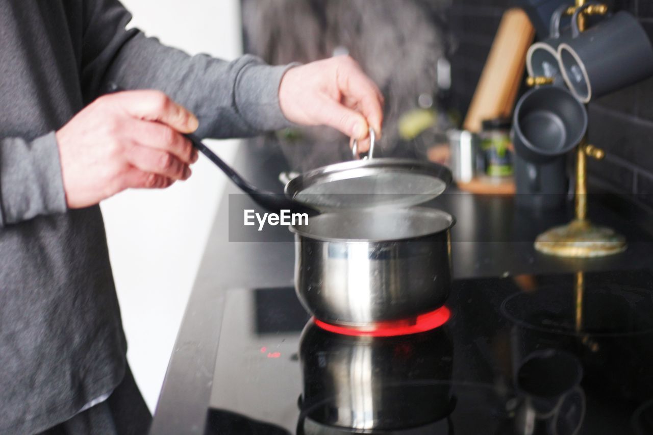 Midsection of person preparing food in kitchen at home