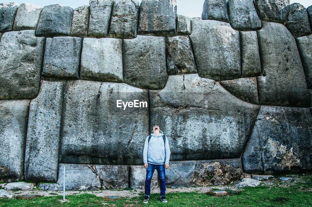 Full length of man standing against stone wall