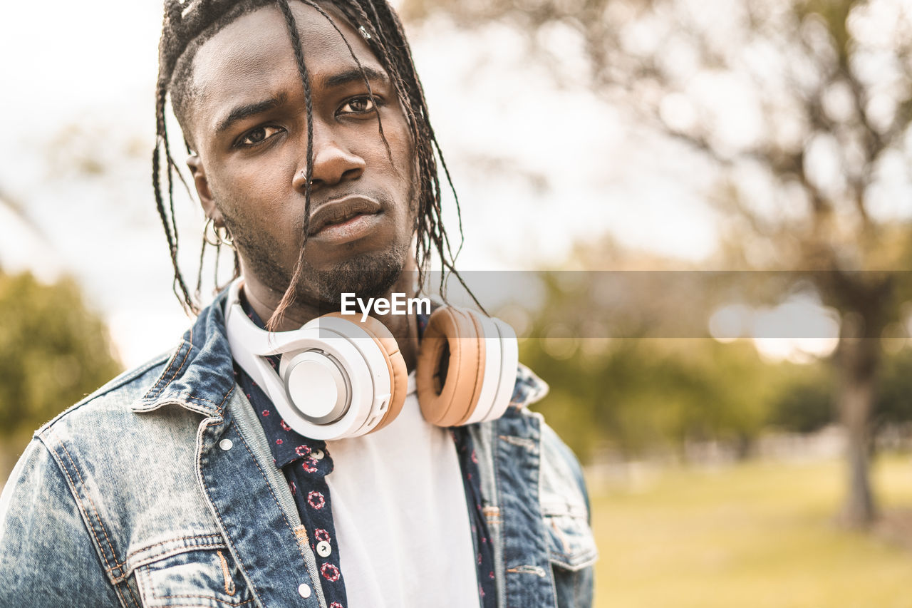 Portrait of young man with headphones standing in city