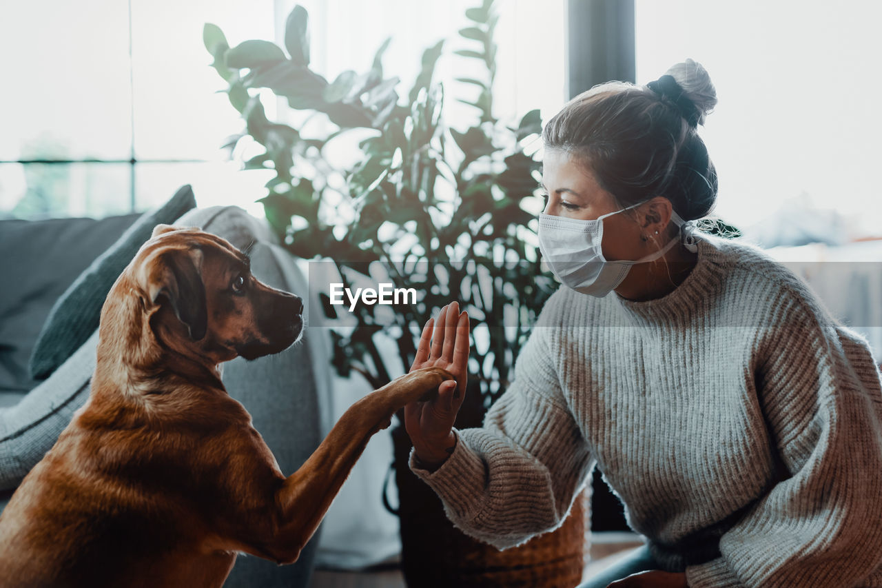 Woman with dog by plant at home