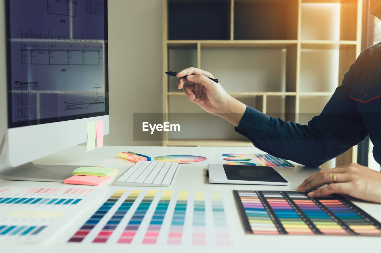 Cropped hand of businesswoman analyzing color swatch at desk in office