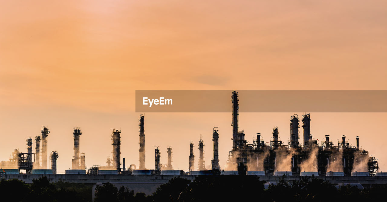 Panoramic view of factory against sky during sunset