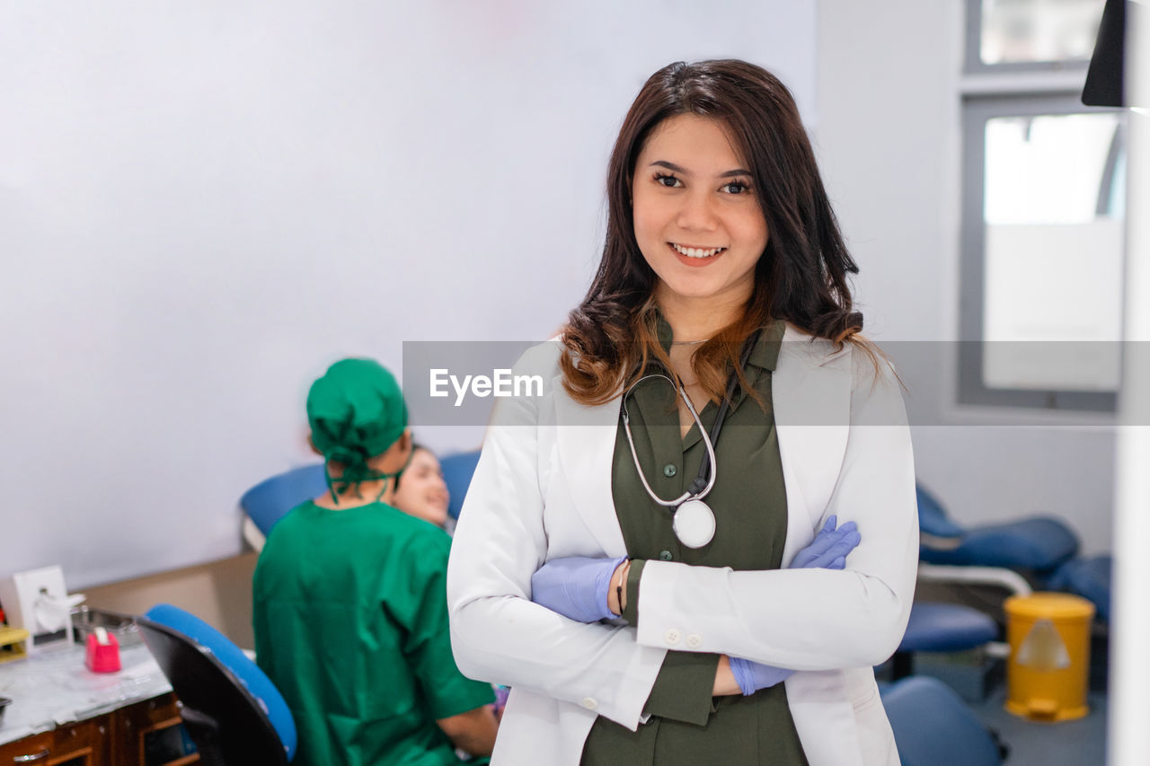 portrait of smiling female doctor standing against white background