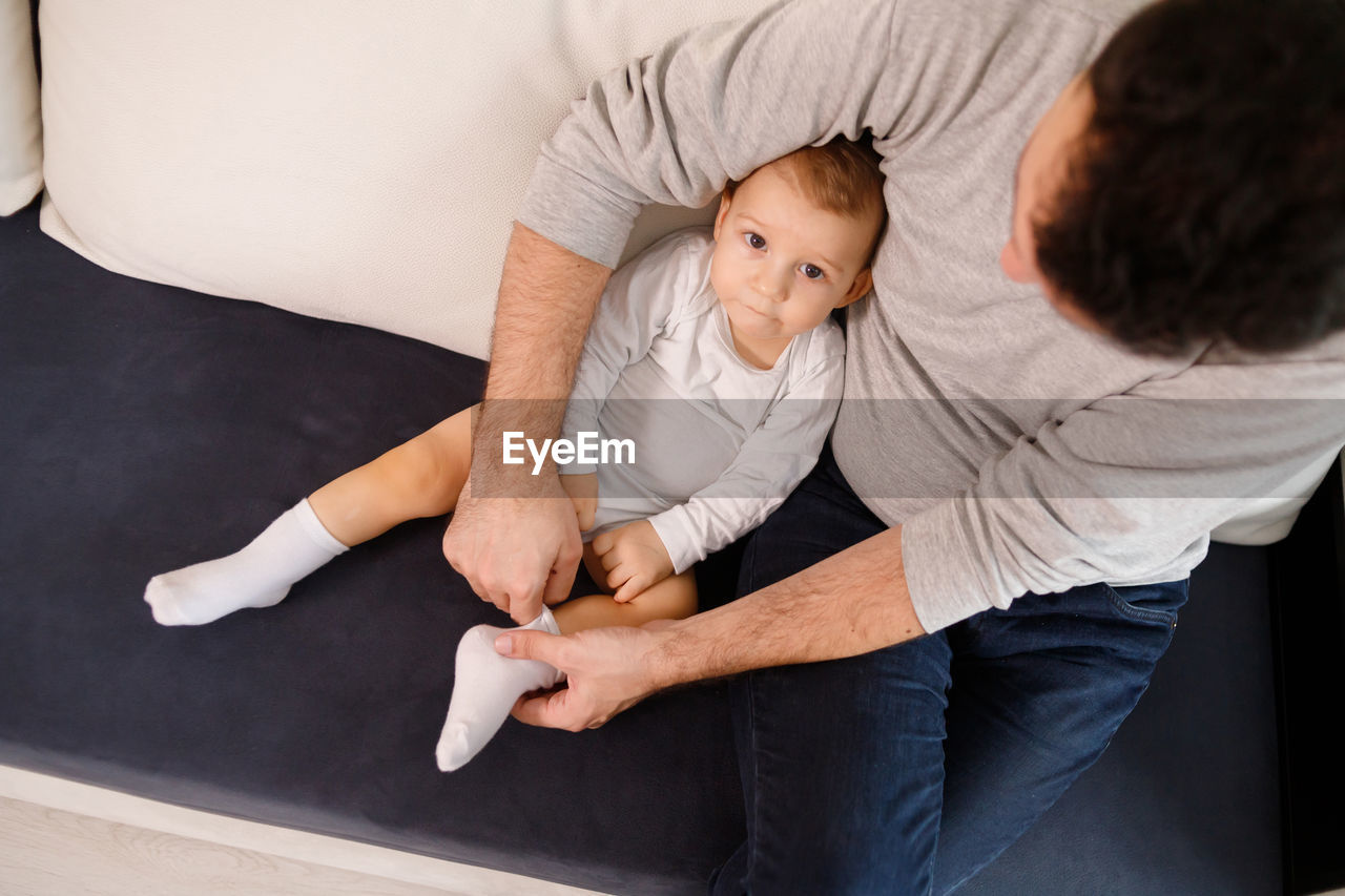 High angle view of father with son sitting on sofa at home