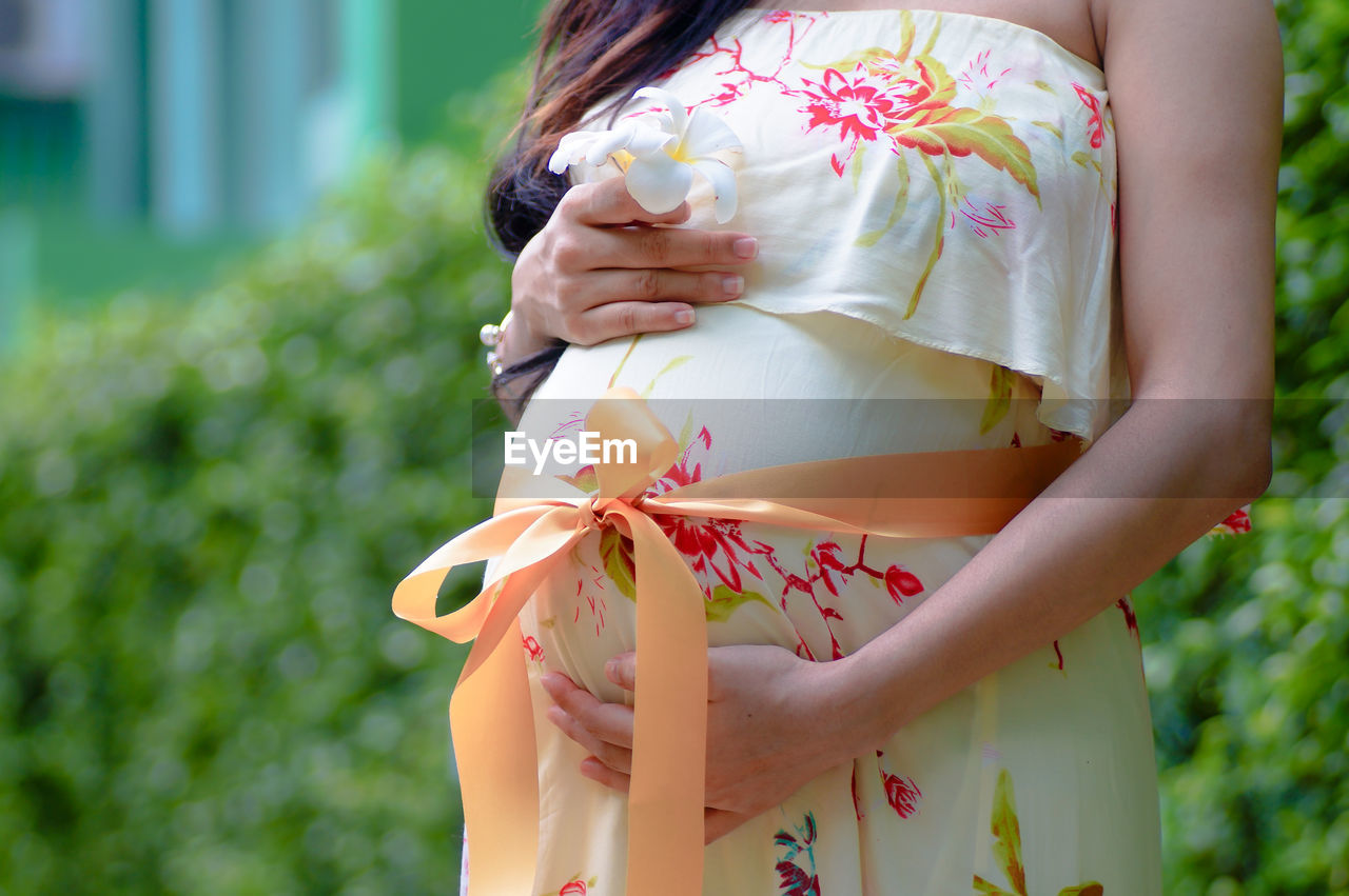 Midsection of pregnant woman standing at park