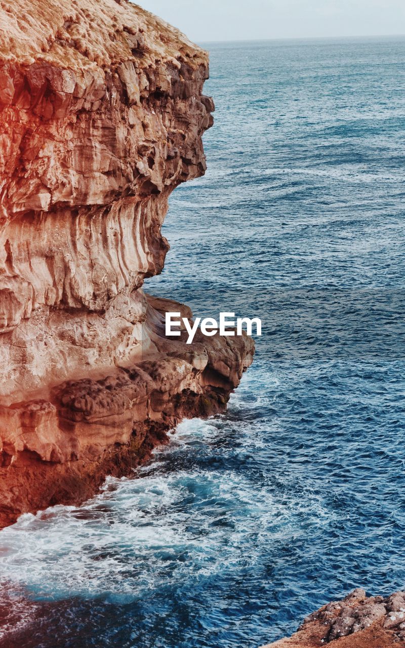 Rock formation in sea against sky