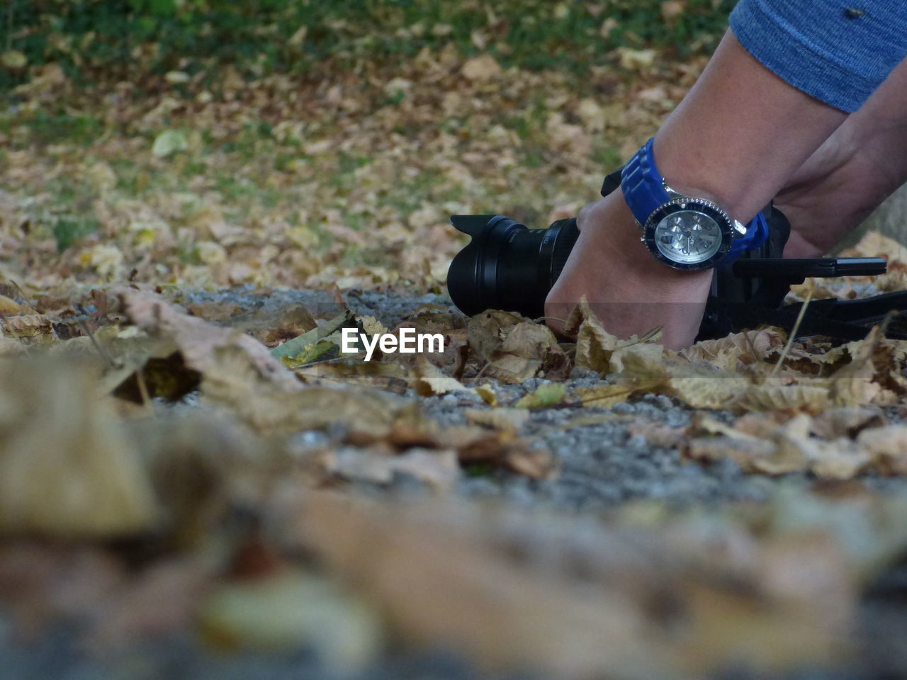 LOW SECTION OF PERSON WEARING SHOES ON DRY LEAVES