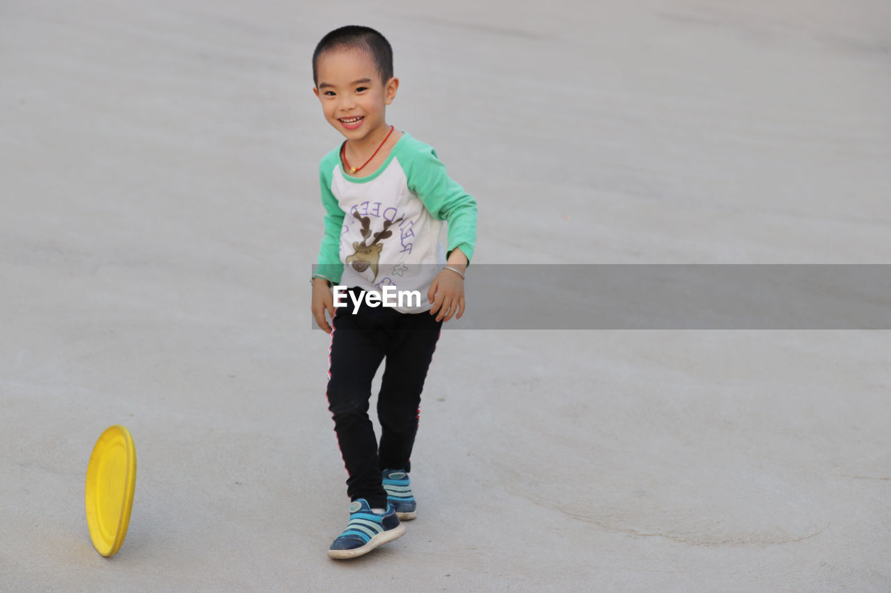 Cheerful boy playing with plastic disc at park