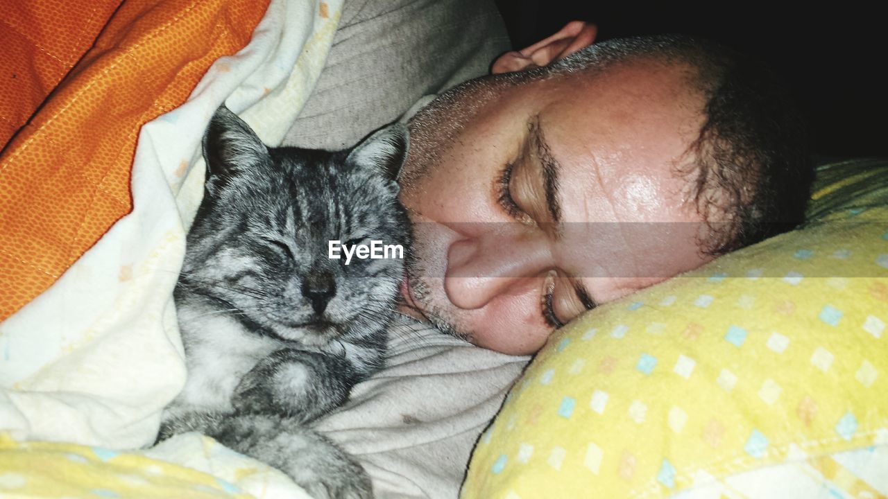 Man and cat sleeping on bed