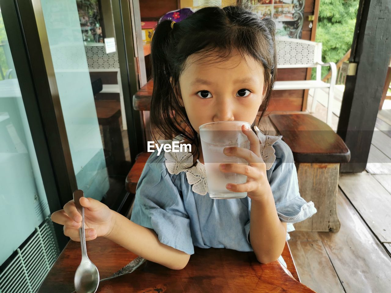 PORTRAIT OF A GIRL DRINKING WATER FROM TABLE