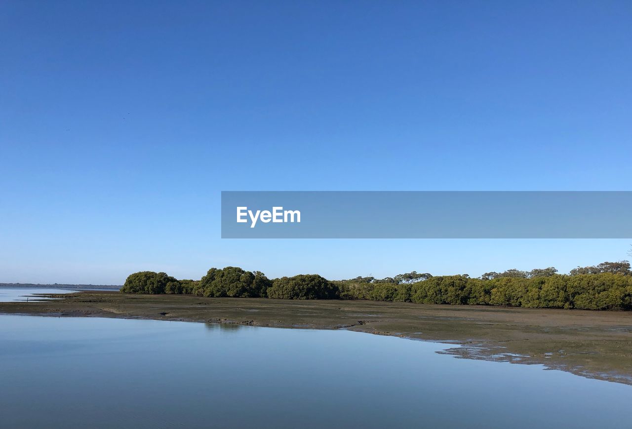 Scenic view of lake against clear blue sky