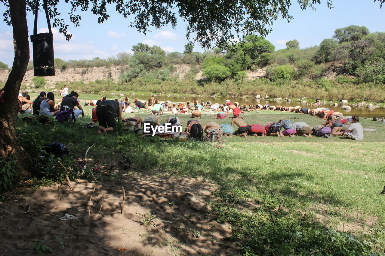 People kneeling and bending on grassy field during religious ceremony