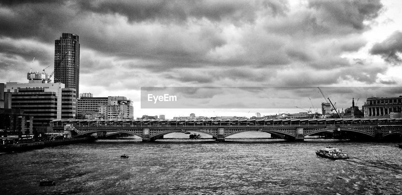 Blackfriars bridge over thames river against cloudy sky in city