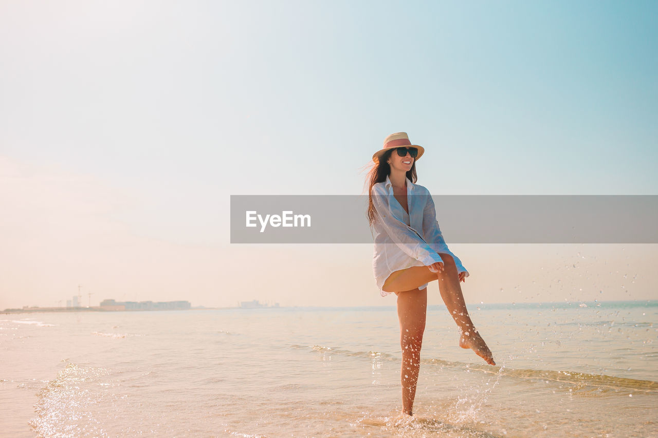 Woman standing at beach against sky