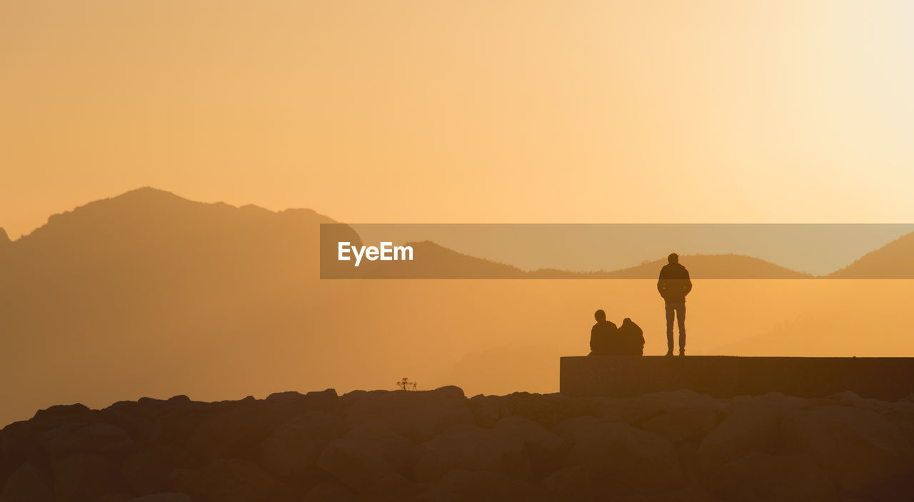 Silhouette people on mountain against clear sky during sunset