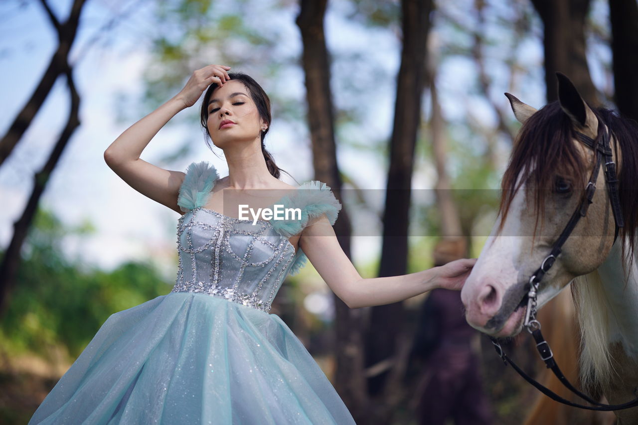 Portrait of a beautiful woman with a horse in the forest background.