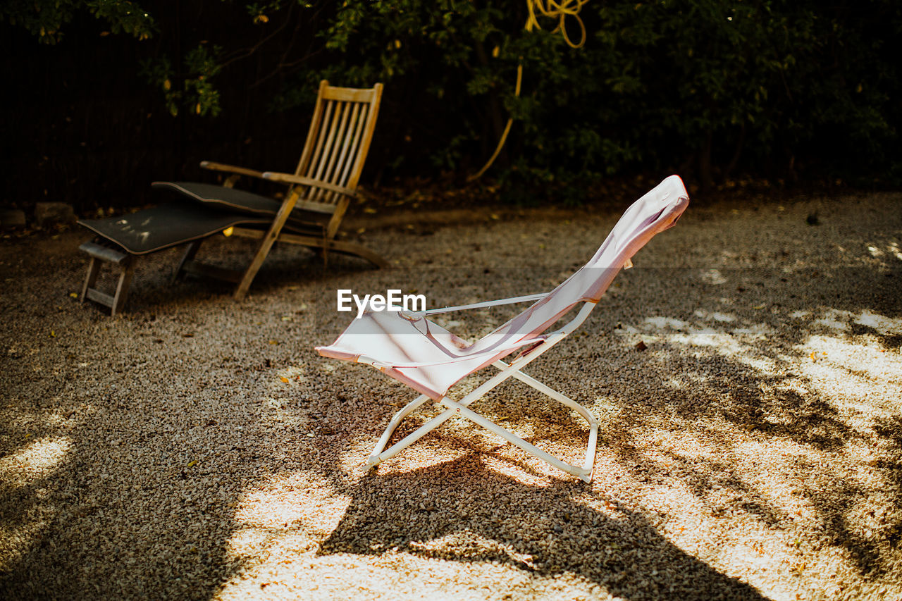 Empty lounge chairs on sand in park