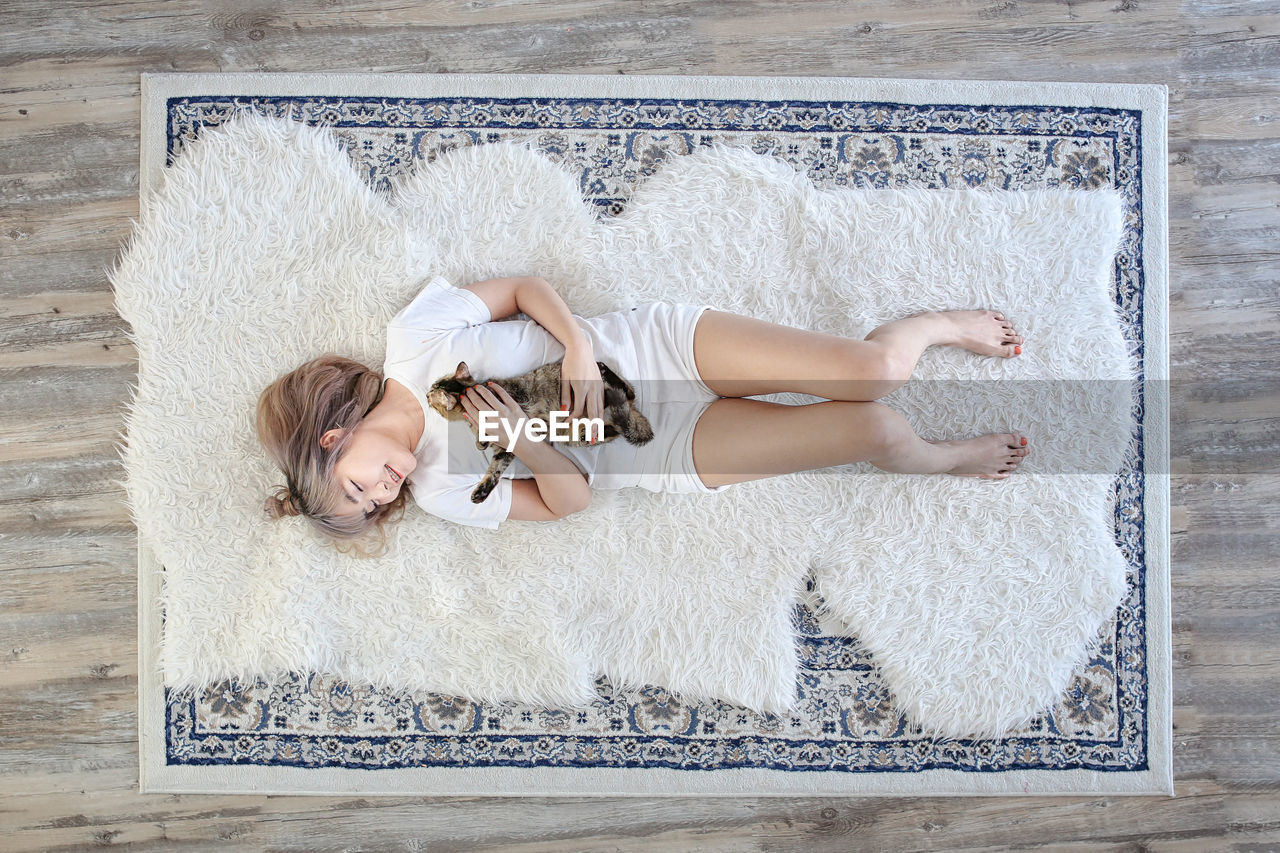 DIRECTLY ABOVE SHOT OF WOMAN LYING ON RUG