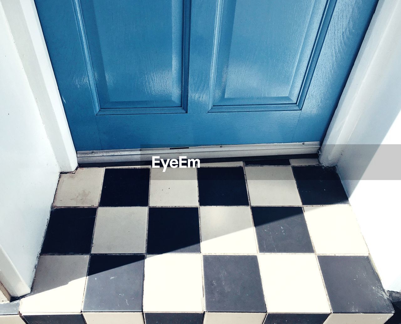 High angle view of checked pattern floor by blue door