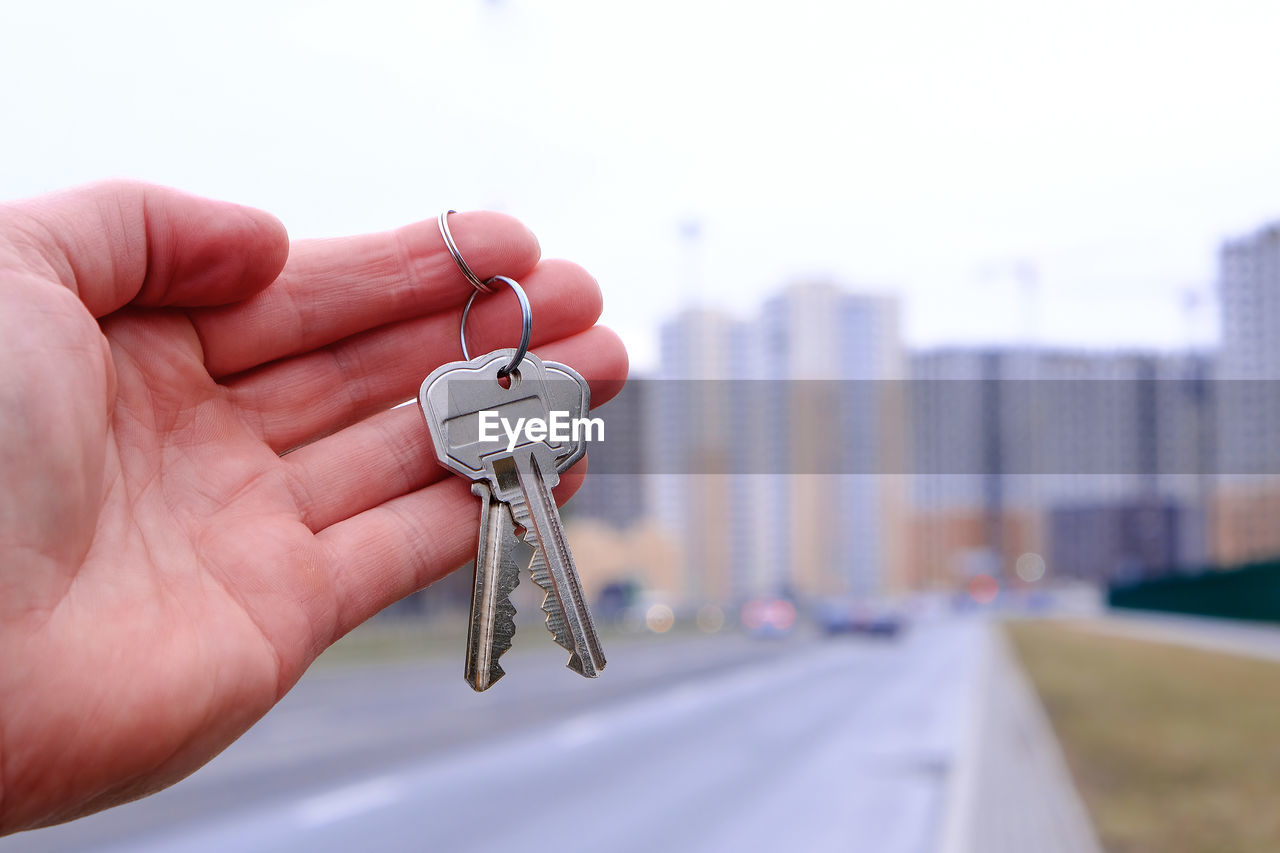 hand, holding, city, architecture, focus on foreground, close-up, one person, building exterior, fashion accessory, built structure, day, finger, adult, outdoors