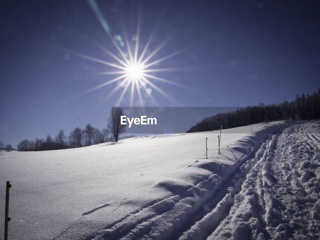 SCENIC VIEW OF SNOW COVERED FIELD AGAINST BRIGHT SUN