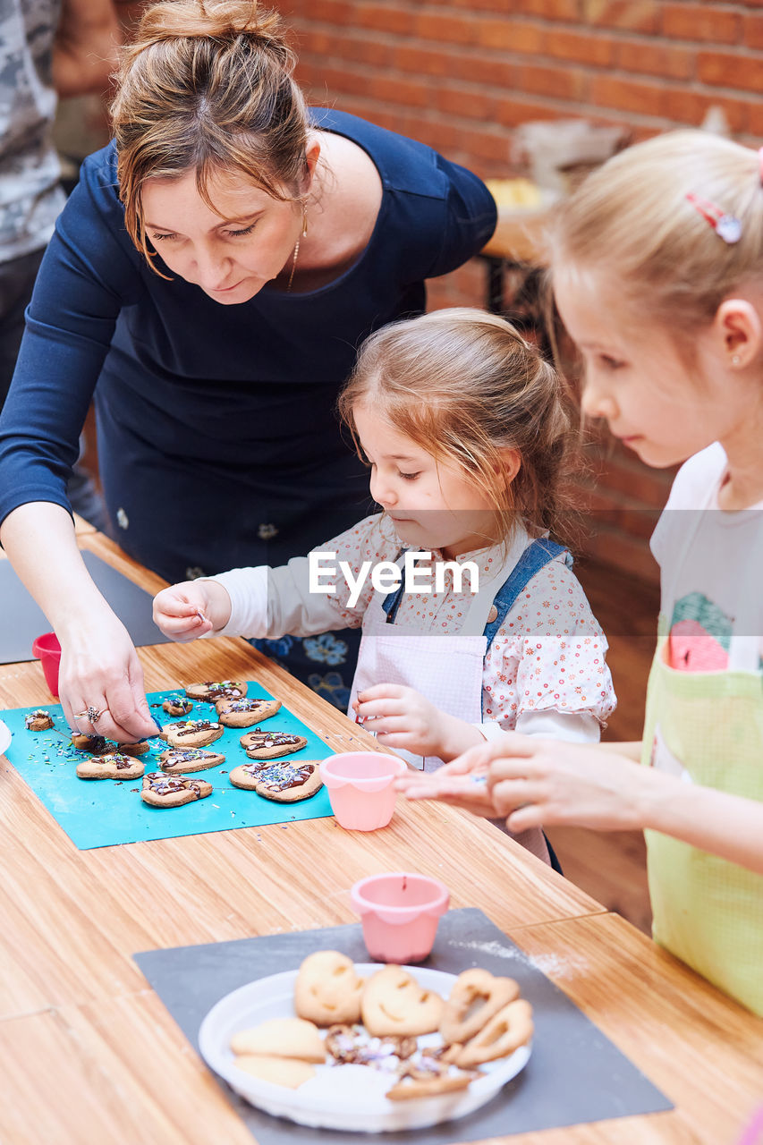 MOTHER AND DAUGHTER ON TABLE WITH PEOPLE