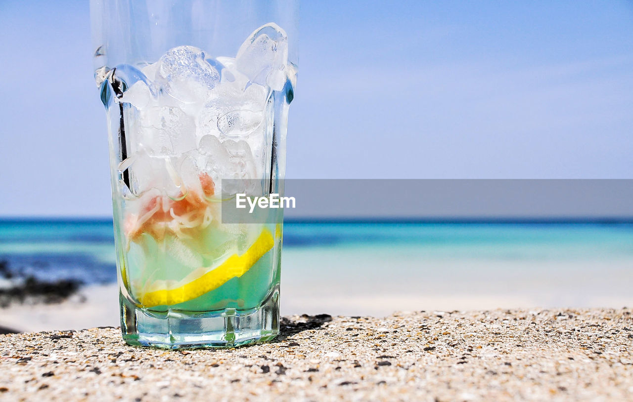 Close-up of drink at beach against sky